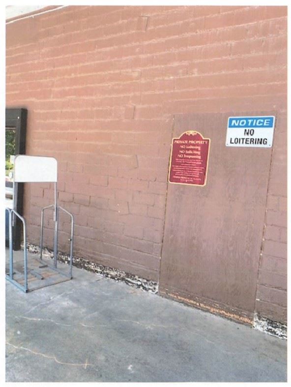 No Trespassing Sign next to No Loitering Sign on wall near back entrance